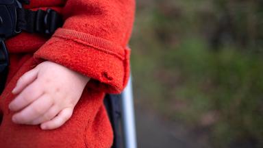 Eine Hand eines Kleinkindes im Kinderwagen